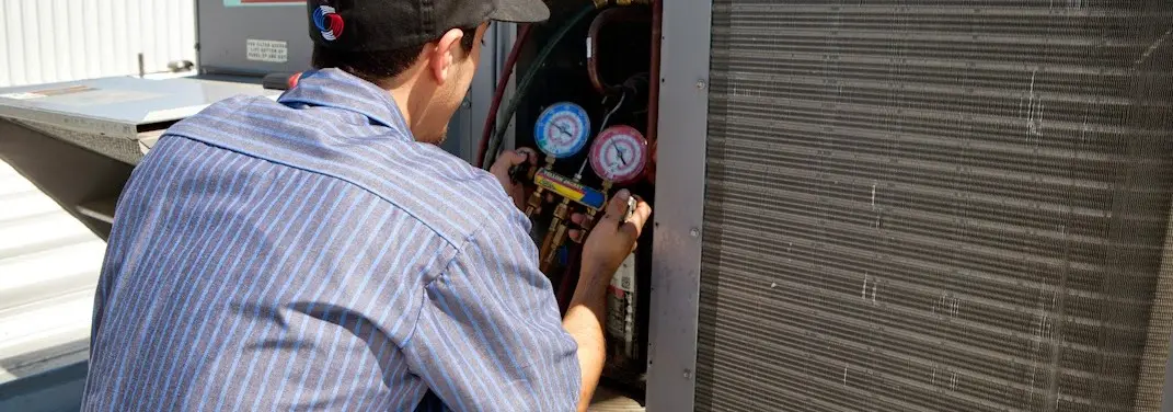 HVAC technician servicing a condenser unit in Laredo