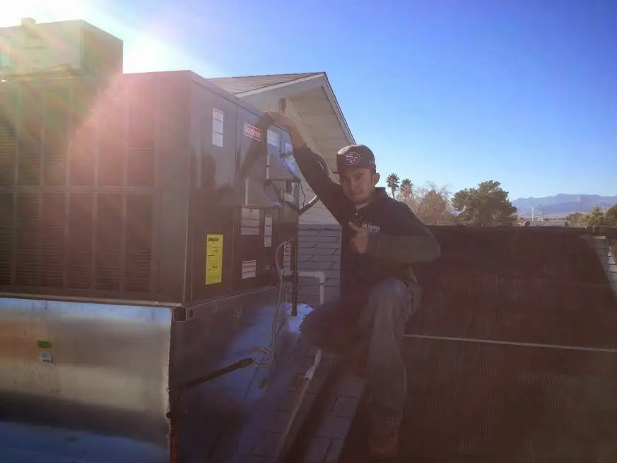 HVAC technician performing AC Tune-Up on a rooftop unit in Laredo